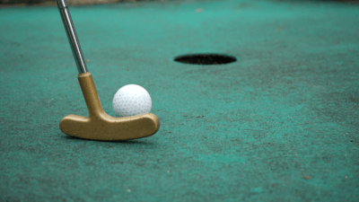 Lähikuva minigolfpallosta, joka putoaa reikään Vilniemen Kyläpirtin radalla.