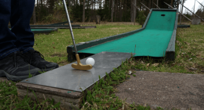 Pelaaja valmiina lyömään minigolfradalla.