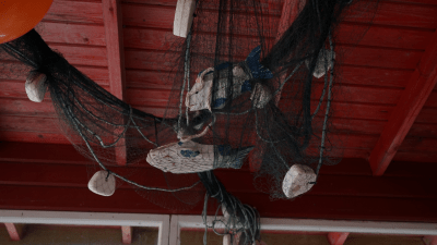 Koristeverkko ja puiset kalat Vilniemen Kyläpirtin terassin katossa.